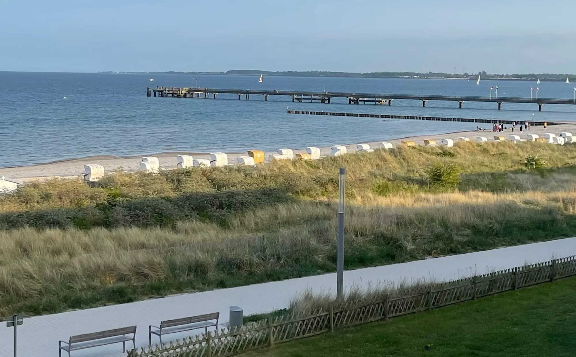 Blick vom Balkon über Promenade, Dünen und Strandkörbe auf die Ostsee und die Seebrücke von Großenbrode