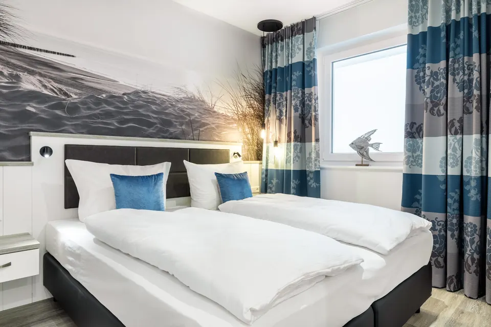Schlafzimmer mit Boxspringbett und blauen Kissen